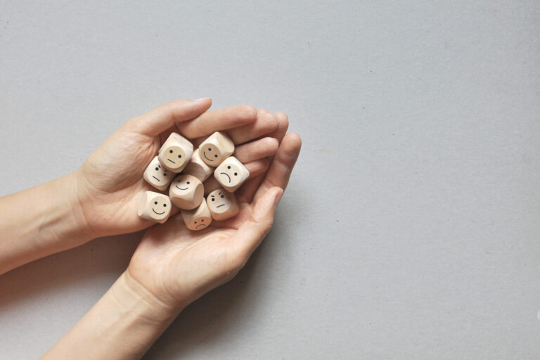 Two hands holding dice with negative and positive faces on them