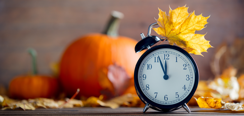 A clock surrounded by fall decor signifying Thanksgiving hours