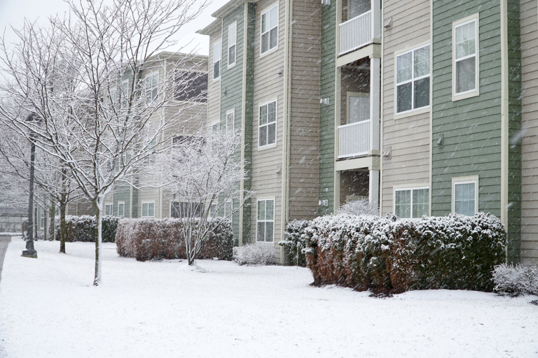 An apartment building surrounded by snow in the winter time