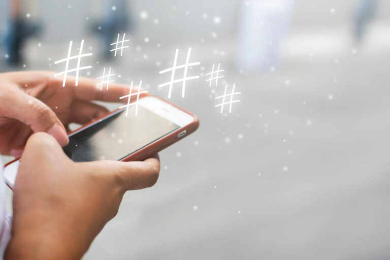 A person holds a cell phone with images of hashtags circling