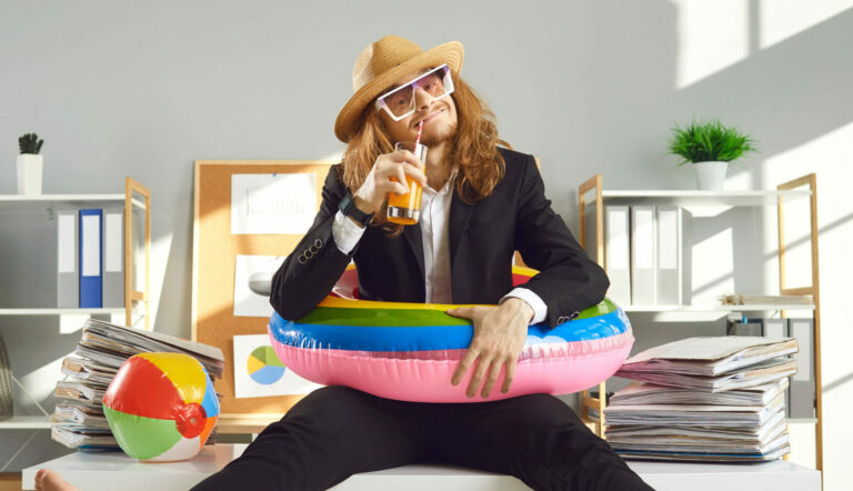 office worker sits on desk with a pool float and a drink