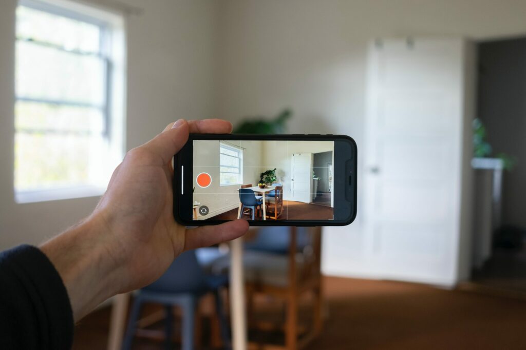 A person holds a smartphone taking a horizontal video of an apartment.