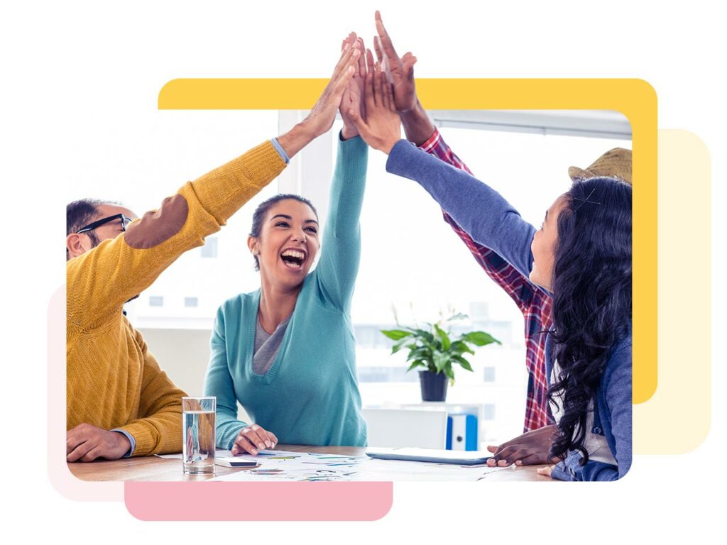 Marketing team at the table giving a group high-five