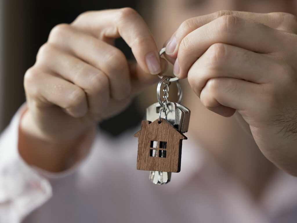 Closeup of hands holding keys with a small house keychain