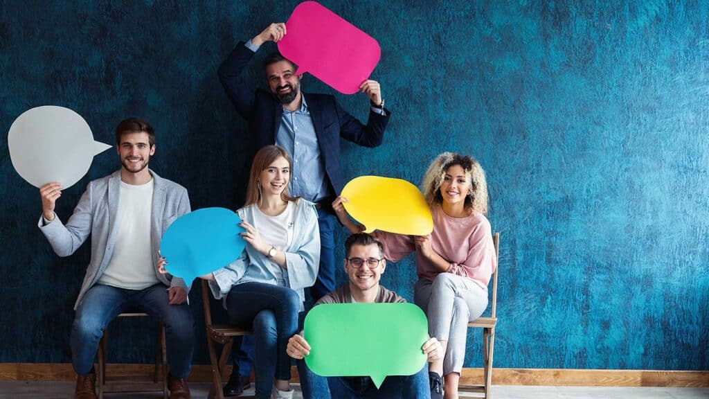 Group of people holding up multi-colored speech bubbles