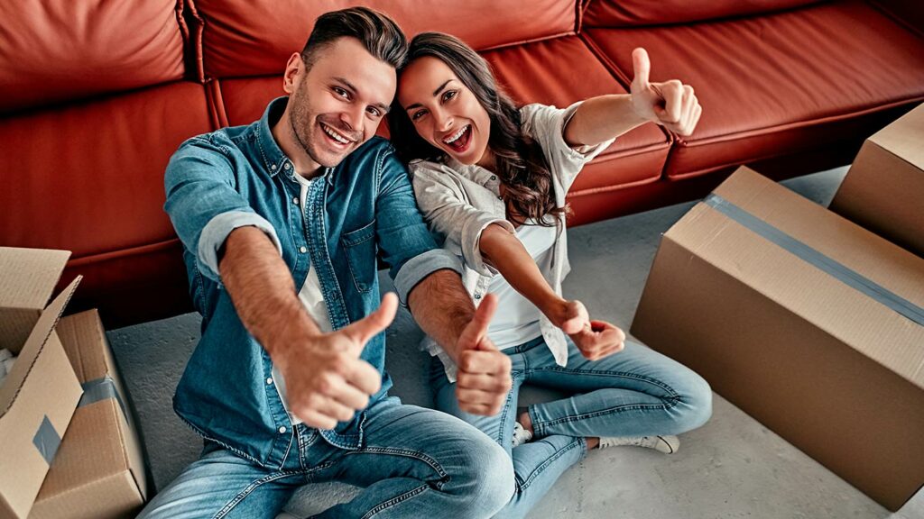 Couple taking a break from unpacking to give thumbs up