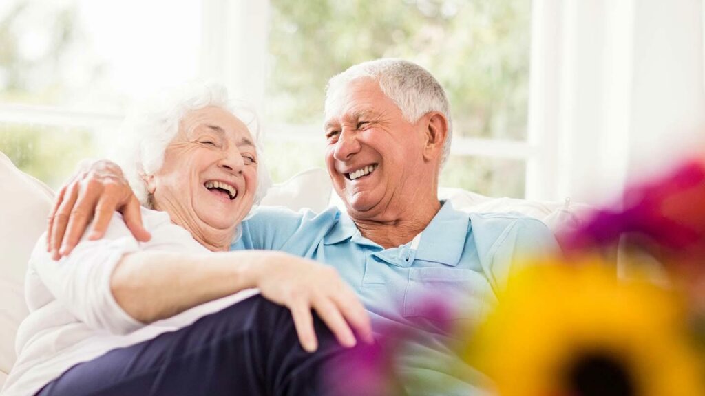 Senior citizen couple laughing on the couch