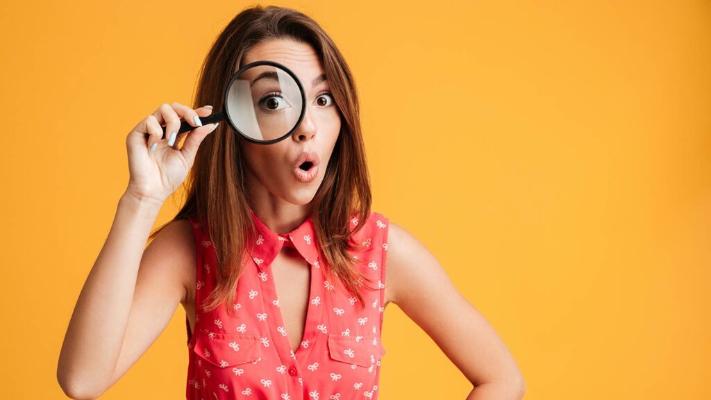 Surprised woman holding a magnifying glass up to her eye