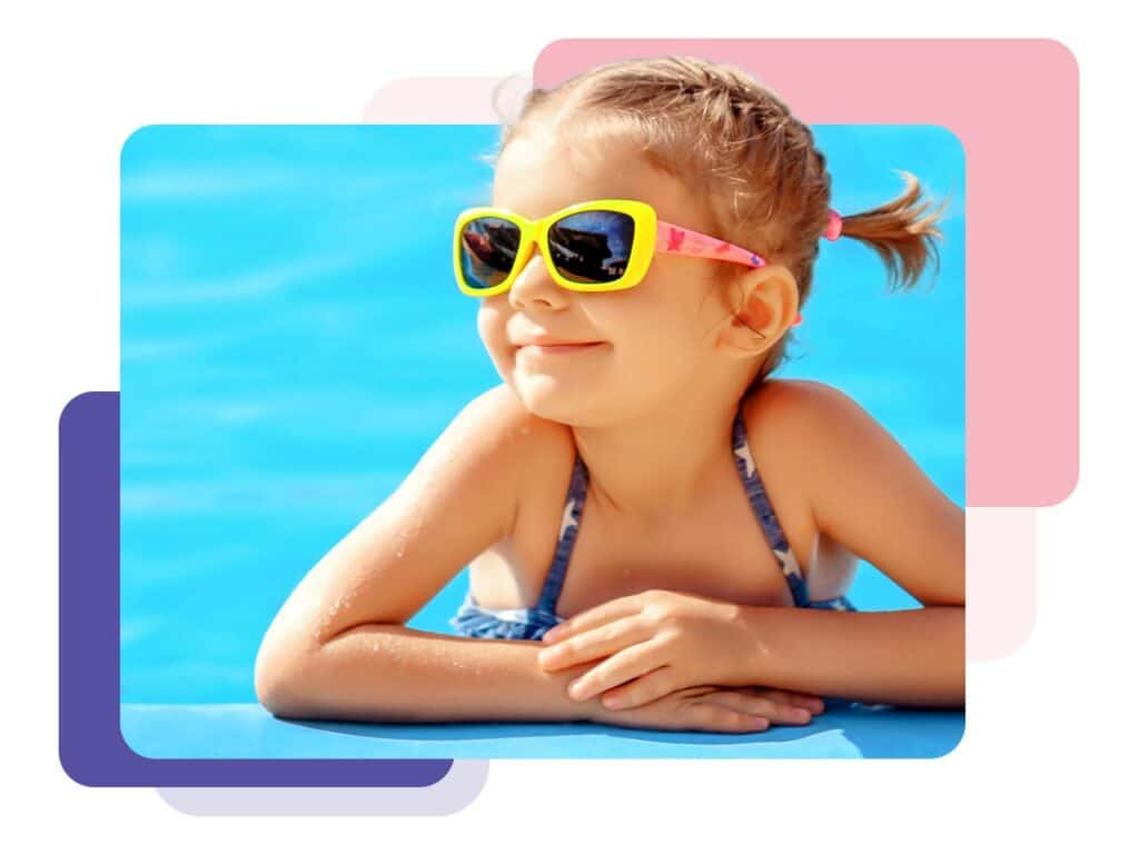 Young girl in sunglass smiling at the edge of a pool