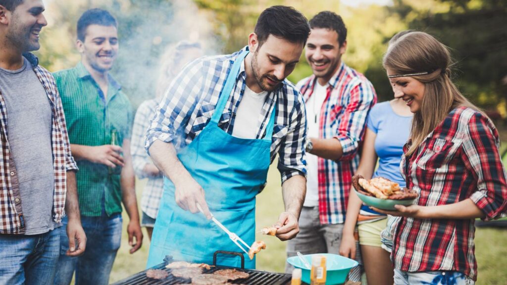 Friends congregating around a grill at a BBQ