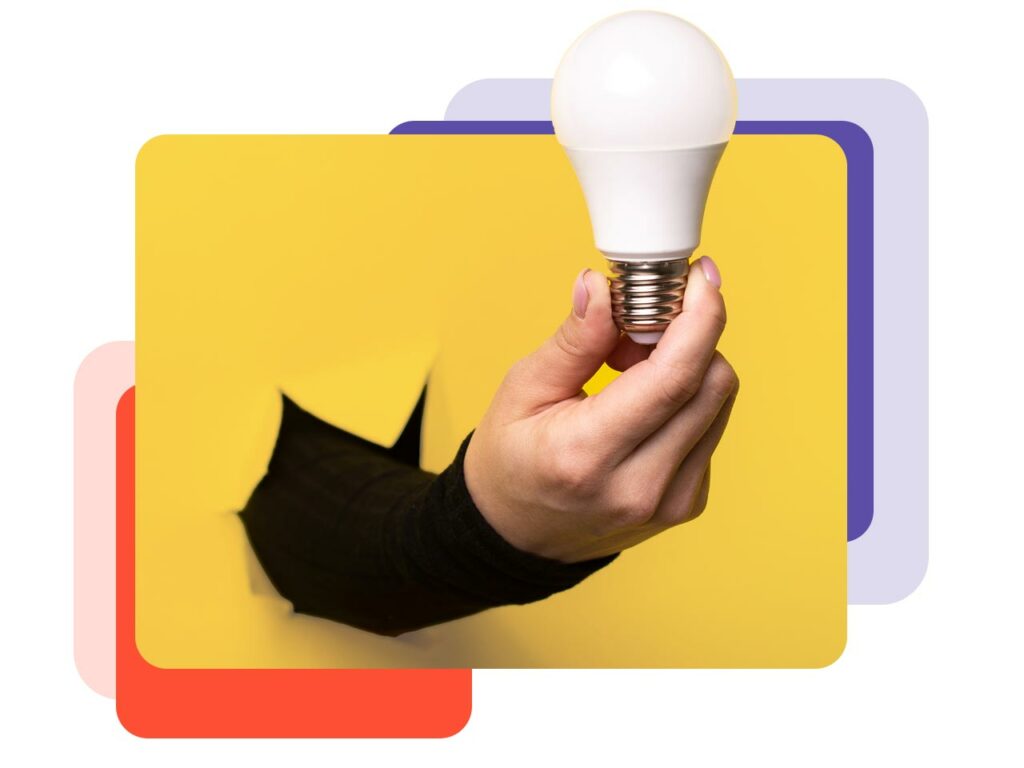 Hand breaking through a yellow wall holding an LED lightbulb