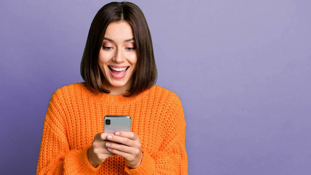 Woman smiling as she uses her cell phone