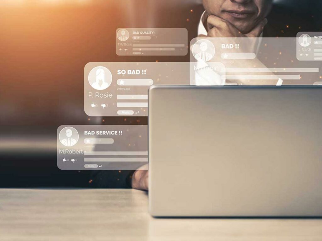 Transparent chat bubbles showing bad reviews superimposed on a photo of a man using a laptop