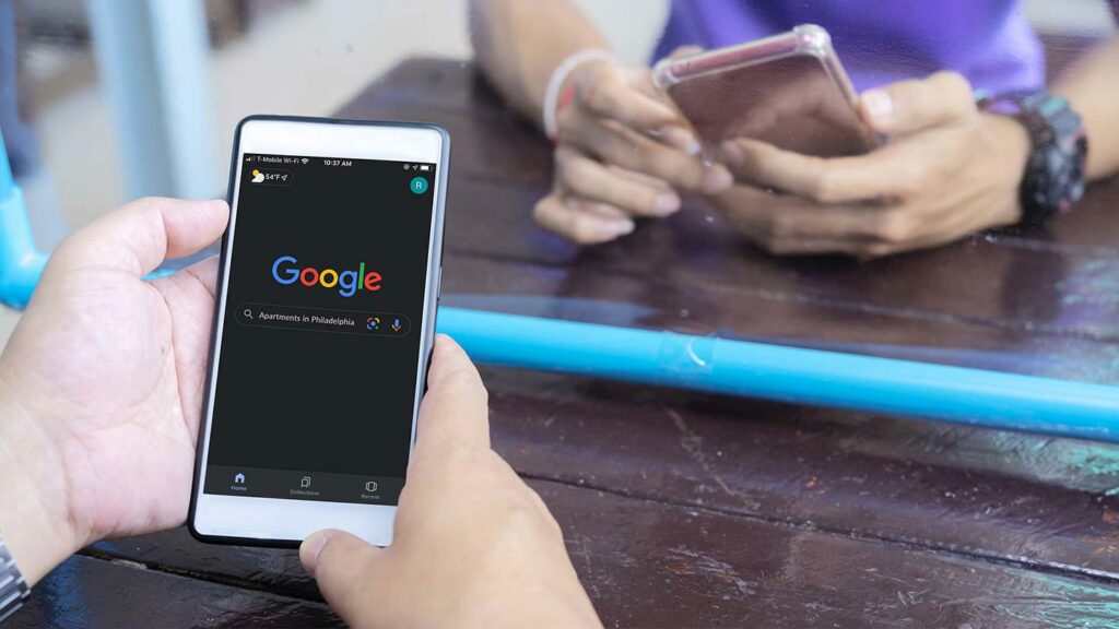 Hand holding a cellphone showing a Google search screen