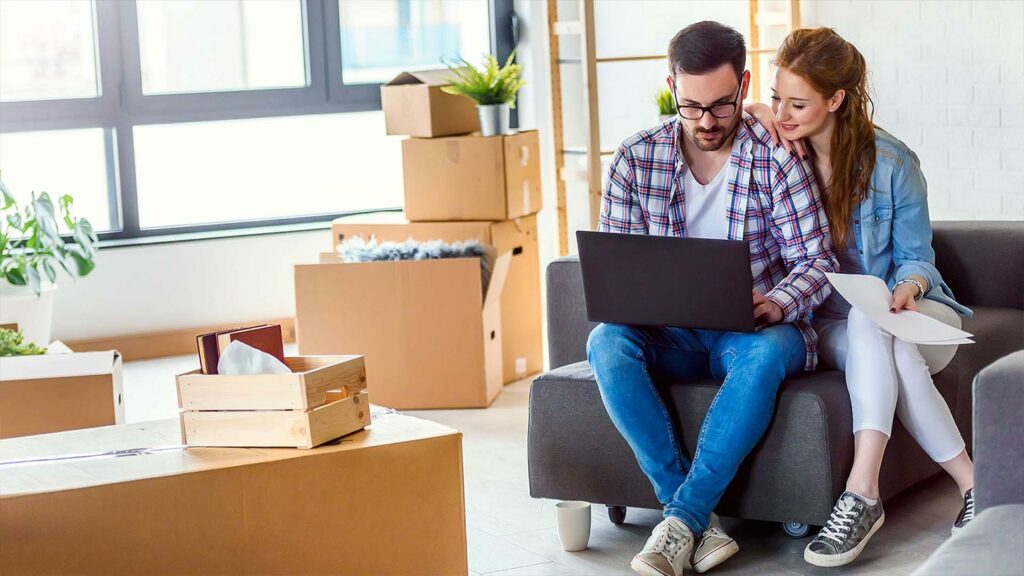 Couple stopping their unpacking to use a laptop