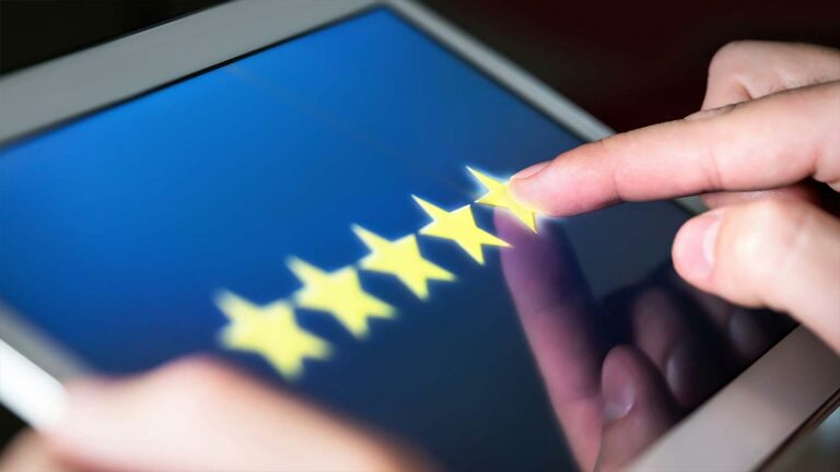 Fingers tapping a 5 star review on a tablet