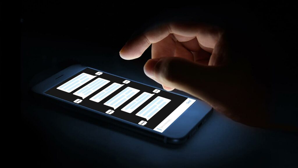 Cell phone chat screen illuminating a hand