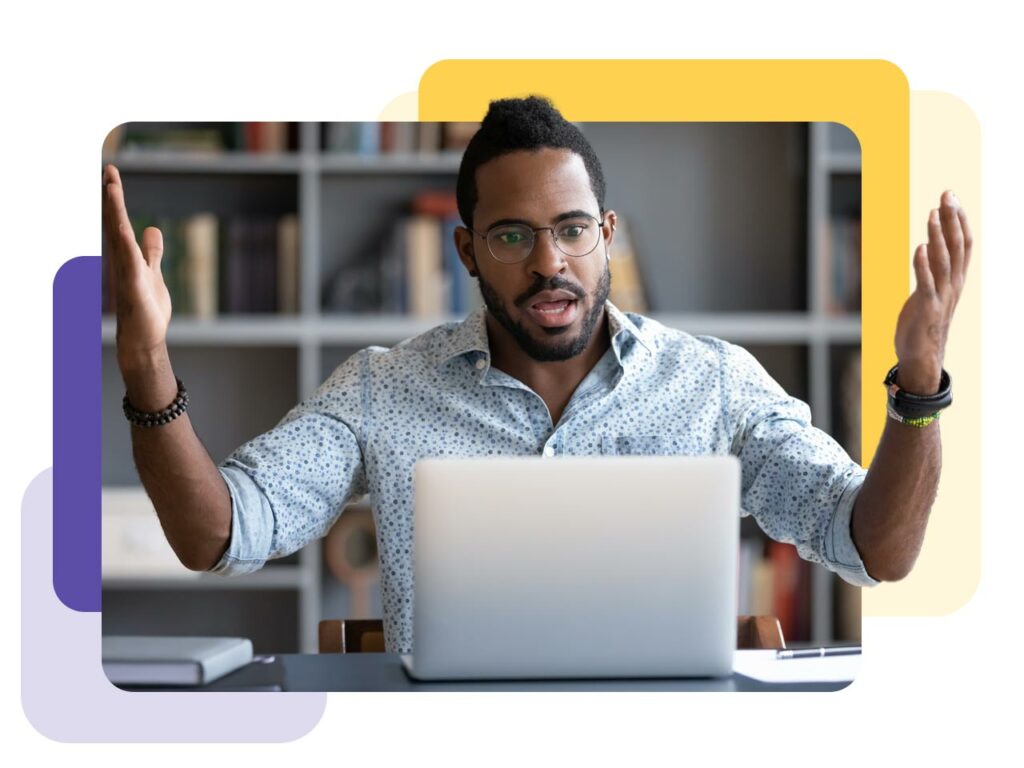 Business professional throwing his hands up in frustration as he works on a laptop