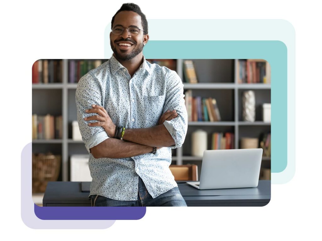 Business professional smiling in front of his desk because he's happy with his new multifamily CRM